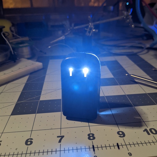 The blobby friend sitting on my desk. The dim lighting allows you to see his glowing eyes.
